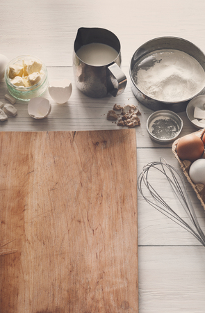Baking background. Cooking ingredients for dough and pastry making and wooden pizza board on white rustic wood. Above view with copy space, mockup for menu, recipe or culinary classes.の写真素材