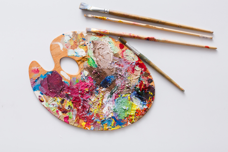 Art palette with colorful paint strokes and paintbrushes on white isolated background, top view, flat lay, objectの写真素材