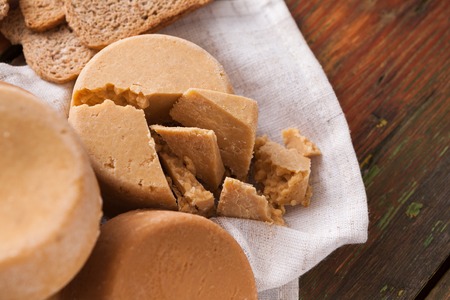 Norwegian homemade brown cheese brunost with crackers or crispbread on wooden desk, close-up, selective focusの写真素材