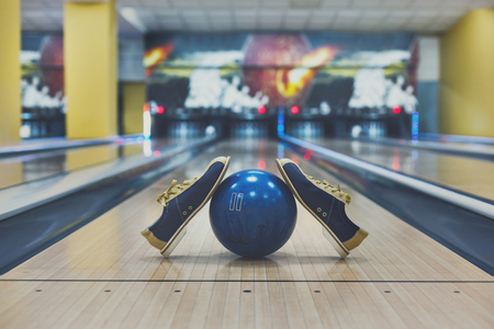 Bowling accessories background. Interior of bowling alley, lane with ball and special shoes closeup, selective focusの写真素材