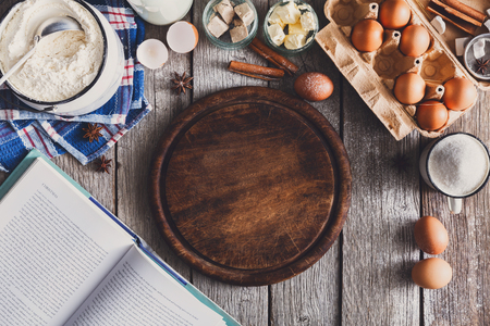 Baking background. Cooking ingredients for dough and pastry making and wooden pizza board on rustic wood. Top view with copy space, mockup for menu, recipe or culinary classes.の写真素材