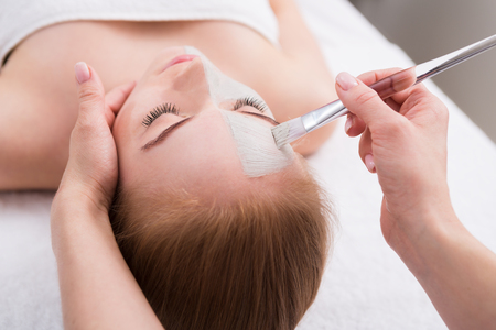 Apply face mask, spa beauty treatment and skincare. Woman getting facial nourishing mask by beautician at spa salon, close-upの写真素材