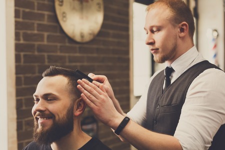 Barber make haircut with scissors in barbershop. Hairstyle in male hair salonの写真素材