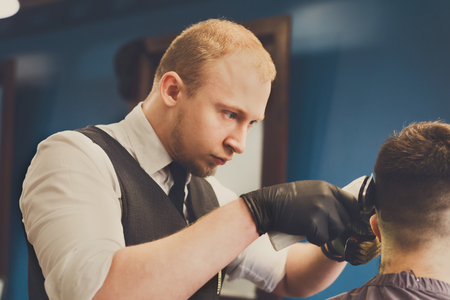 Man getting haircut by hairstylist at barbershop. Stylish barber and clientの写真素材