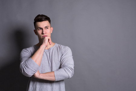 Pensive young man portrait in casual at gray studio background. Boy fashionの写真素材
