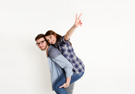 Loving couple piggybacking. Happy young man with his girlfriend, white isolated studio background, copy spaceの写真素材