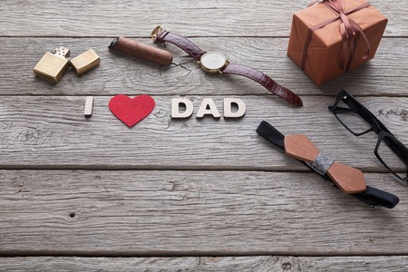 Happy Fathers Day card with male presents, love dad letters, watch and other man things on rustic wood backgroundの写真素材