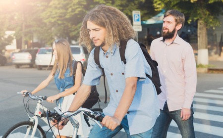 Young people riding on bikes. Company of friends walk with bicycles, crossing the crosswalk. Healthy lifestyle, leisure, sport conceptの写真素材