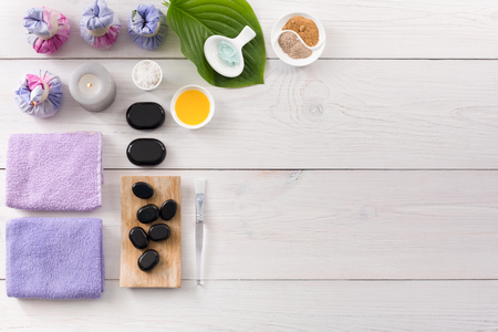 Spa treatment and aromatherapy top view background with copy space on white wood. Zen black stones, aroma salt, herbal balls for indian spaの写真素材