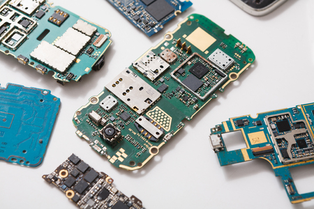 Digital gadgets components, repair shop concept. Motherboards of disassembled smartphones on service...