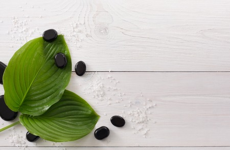 Spa treatment and aromatherapy top view background. Zen black marble stones, aroma salt for wellness beauty parlor. White wood with copy spaceの写真素材