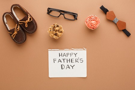 Happy Fathers Day flat lay card with male things and chils shoes on beige backgroundの写真素材