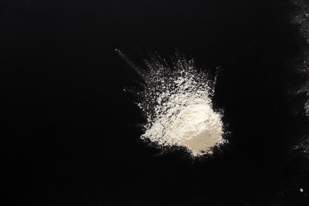 White flour splash spot on black background. Top view on blackboard. Baking concept, cooking dough or pastry.の写真素材