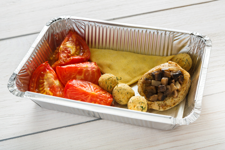 Healthy eating concept. Lunch foil box with stuffed chicken with mushroomes, meatballs and tomatoesの写真素材