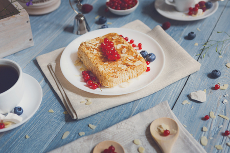 Pastry pie and berries - cowberry, red currant and bluberries. Beautiful food served at blue rustic wooden table, cake dessert at ethnic porcelain plate, tea and coffee cup.の写真素材