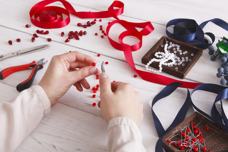 Woman making jewelry, home workshop. Artisan pov, female hands creating accessory with beads and...