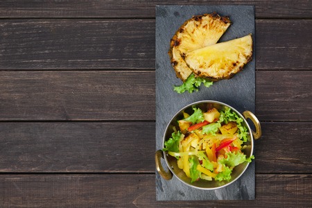 Vegetarian indian food. Healthy vegan salad with orange and vegetables in copper bowl on wooden table, top viewの写真素材