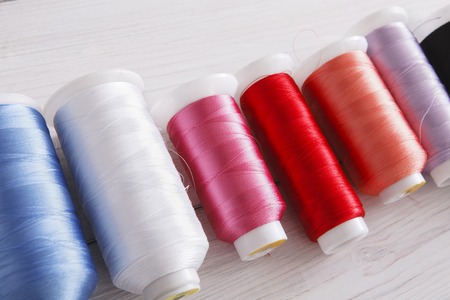 Colorful thread spools on wooden table close up. Sewing string. Art, handicraft concept