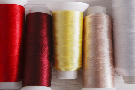 Colorful thread spools on wooden table close up. Sewing string. Art, handicraft concept