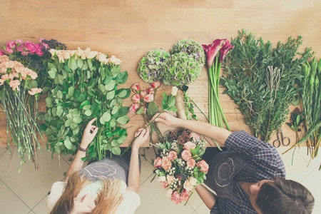 Flowers delivery shop top view. Florists creating order, making rose bouquetの写真素材