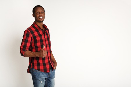 I like it. Happy smiling black man showing thumb up gesture, boy in checkered shirt, standing on white background, studio shotの写真素材