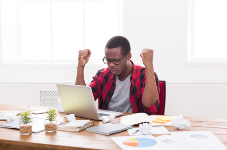 Disappointed black businessman in office, in casual, work with laptop, solving a problemの写真素材
