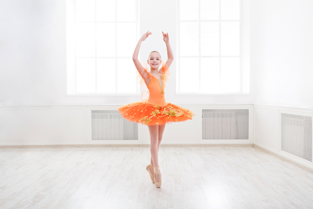 Young teenager ballerina practicing classical dance pas in studio before performance. Ballet student exercising in ballet costume, standing on her toes.の写真素材