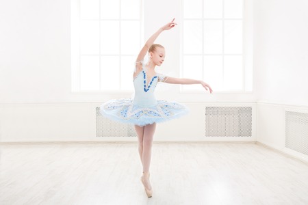 Young teenager ballerina practicing classical dance pas in studio before performance. Ballet student exercising in ballet costume, standing on her toes.の写真素材