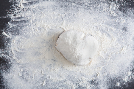 Homemade bakery. Top view of raw dough on black table covered with flour, baking background, closeup, copy spaceの写真素材