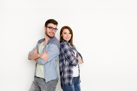 Portrait of happy couple with arms crossed standing back to back isolated at white background, studio shotの写真素材