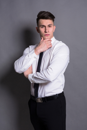 Successful businessman. Confident young man standing at gray studio backgroundの写真素材