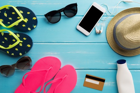 Vacation background on blue wood, top view with copy space. Flip flops, sunglasses and straw hat....