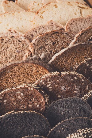 Sliced black bread gradient background. Bakery and grocery concept. Fresh, healthy whole grain sliced sorts of rye and white loaves on woodの写真素材
