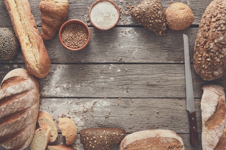 Fresh bread frame background, top view with copy space. Homemade baguette loaves on rustic woodの写真素材