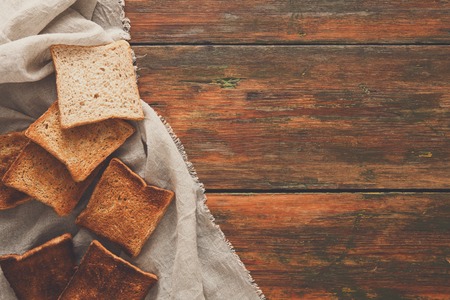 Toasted slices of white bread on sackcloth on rustic wooden table. Still life, top view, copy spase, bakery and grocery backgroundの写真素材