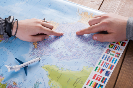Couple planning airplane trip to Canada, point on map, taking notes in blank notebook, copy space