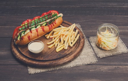 Hot dog and french fries. American fast food restaurant cuisine on wooden platter on table.の写真素材