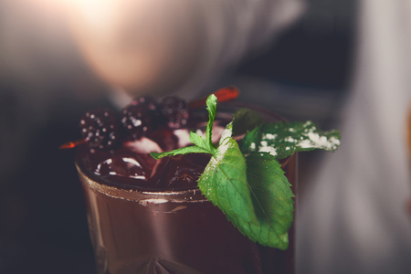 Healthy sweet berry cocktail with mint and blackberry at blurred bar background.の写真素材