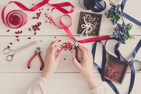 Woman making jewelry, home workshop. Artisan pov, female hands creating accessory with beads and ribbons, top view. Beauty, creativity, handicraft conceptの写真素材