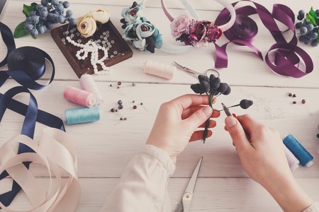 Master making handmade jewelry, woman pov. Needlewoman workplace with plastic beads, flowers and tools for creating accessoriesの写真素材