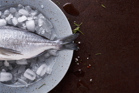 Raw dorado tail on ice in gray platter at black background. Minimalistic mokeup for seafood restaurant or fish market. Top view, copy spaceの写真素材