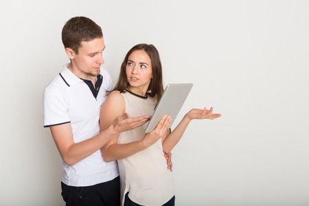 Shocked couple using laptop. Young man and woman unpleasantly surprised while doing online shopping, copy spaceの写真素材