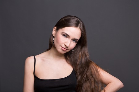 Young woman studio portrait on dark background. Beautiful brunette girl in black.