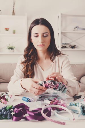 Handmade headbands making, home workshop. Young woman artisan decorating hair hoop with flowers and ribbons. Art, handicraft, creative conceptの写真素材