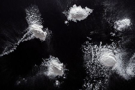 White flour splash spot on black background. Top view on blackboard. Baking concept, cooking dough or pastry.の写真素材