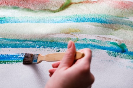 Artist creating watercolor painting. Expressive brush strokes of blue aquarelle on paper texture. Modern art backgroung with copy spaceの写真素材