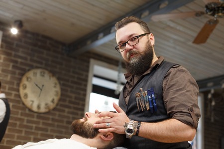 Barber styling beard at barbershop. Stylish hairdresser in male hair salonの写真素材