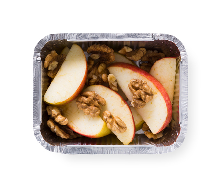 Healthy lunch in foil container. Healthy food take away and delivery. Apples and walnuts in box on white background, closeup, isolatedの写真素材