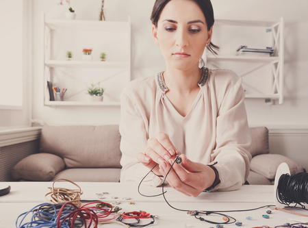 Handmade jewelry making, female hobby. Young woman creating bracelets at home workshop. Fashion,...