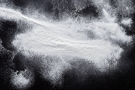 Abstract background. Wheat flour on black. Top view on blackboard. Baking concept, cooking dough or...